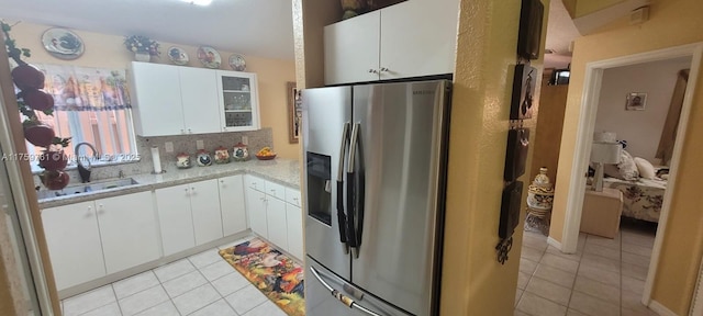 kitchen featuring light countertops, light tile patterned flooring, a sink, and stainless steel fridge with ice dispenser