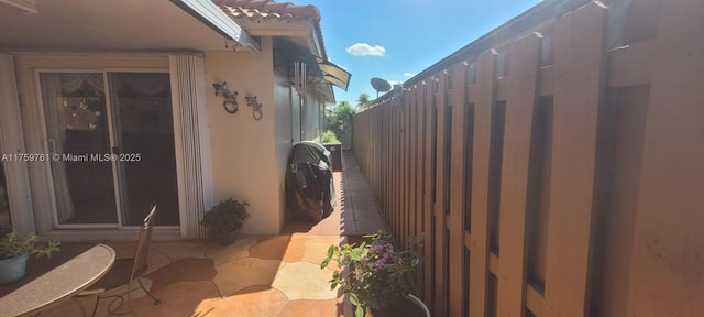 view of side of property featuring fence, a tiled roof, and stucco siding