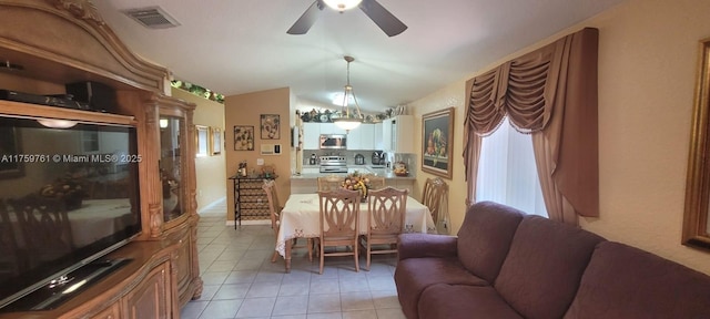 dining room with lofted ceiling, light tile patterned floors, visible vents, and ceiling fan with notable chandelier