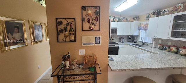 kitchen featuring light tile patterned floors, tasteful backsplash, appliances with stainless steel finishes, white cabinetry, and a sink