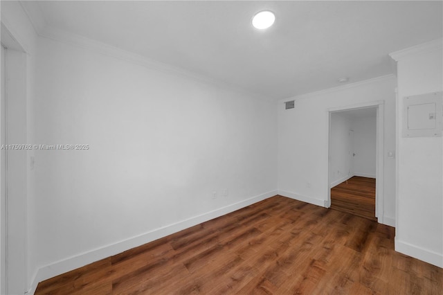 spare room featuring baseboards, wood finished floors, visible vents, and crown molding