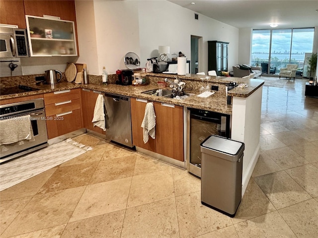 kitchen featuring stainless steel appliances, floor to ceiling windows, brown cabinetry, and a peninsula