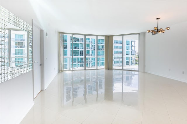 tiled spare room with an inviting chandelier, expansive windows, and baseboards