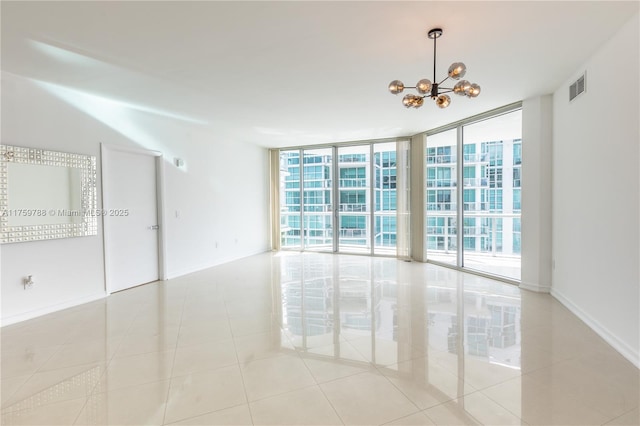 empty room featuring tile patterned flooring, visible vents, baseboards, floor to ceiling windows, and an inviting chandelier