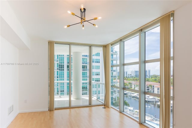 doorway to outside featuring a water view, wood finished floors, visible vents, baseboards, and a wall of windows