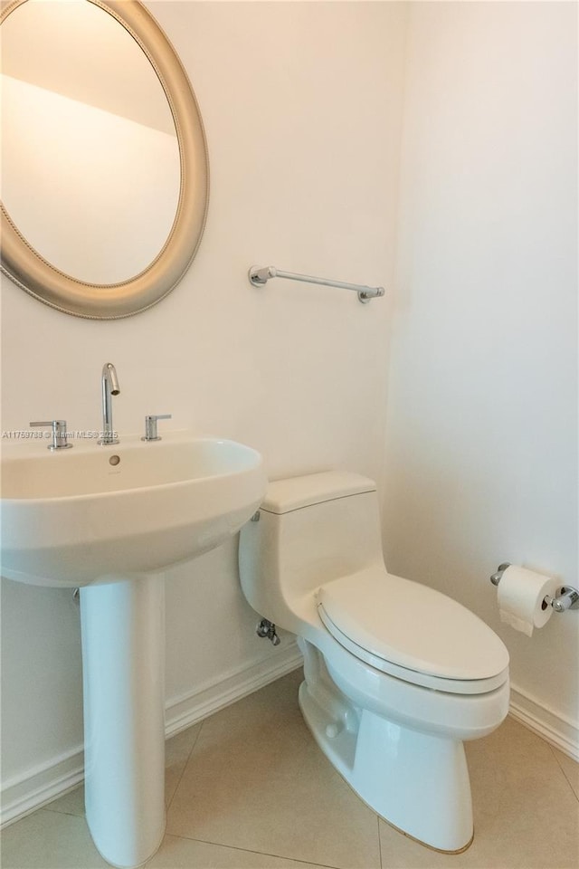 bathroom with baseboards, a sink, toilet, and tile patterned floors