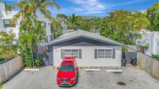 view of front of home featuring a fenced backyard, uncovered parking, and stucco siding