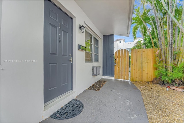 property entrance featuring a gate and stucco siding