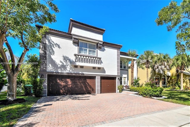 mediterranean / spanish home featuring a garage, a balcony, decorative driveway, and stucco siding