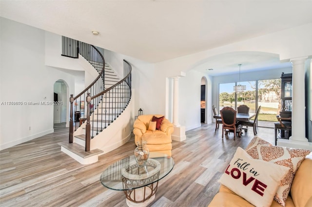 living room with ornate columns, arched walkways, and wood finished floors