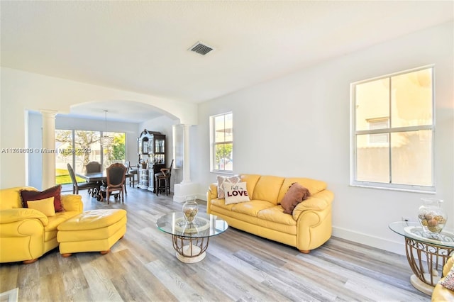 living room with arched walkways, plenty of natural light, and decorative columns