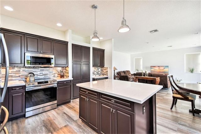 kitchen with visible vents, backsplash, light wood-style flooring, appliances with stainless steel finishes, and a kitchen island