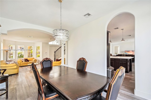 4951 SW 158th Ave, Miramar, FL 33027 - dining area featuring arched walkways, light wood-style flooring, stairway, and a chandelier