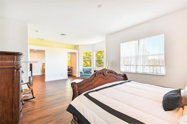 bedroom with baseboards, visible vents, and wood finished floors