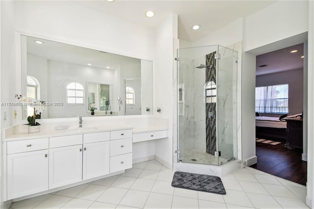 bathroom featuring tile patterned flooring, a marble finish shower, vanity, and ensuite bath