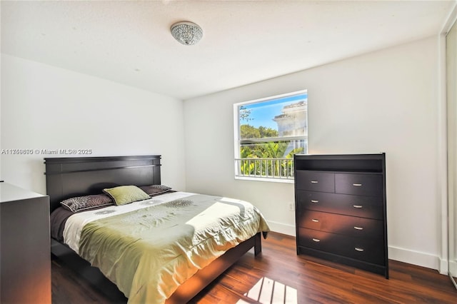 bedroom featuring dark wood finished floors and baseboards