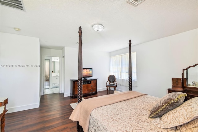 bedroom with a textured ceiling, wood finished floors, visible vents, and baseboards