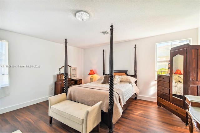 bedroom featuring dark wood-type flooring, visible vents, a textured ceiling, and baseboards