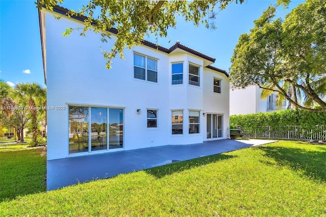 back of property with a patio area, fence, a lawn, and stucco siding