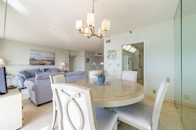dining area featuring a chandelier, a textured ceiling, and light tile patterned floors