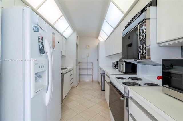 kitchen with light countertops, white appliances, light tile patterned flooring, and white cabinetry