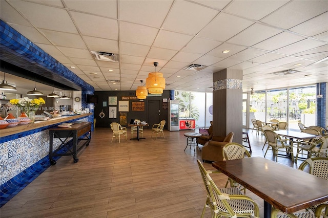 dining room with a paneled ceiling, wood finished floors, and visible vents