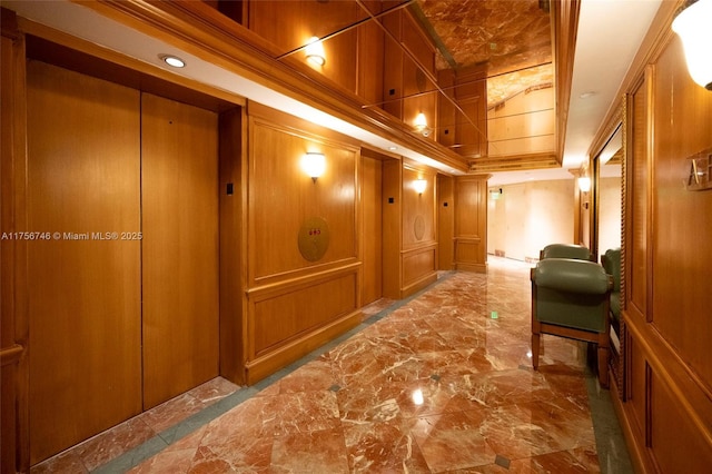 hallway featuring ornamental molding, marble finish floor, a raised ceiling, and a decorative wall