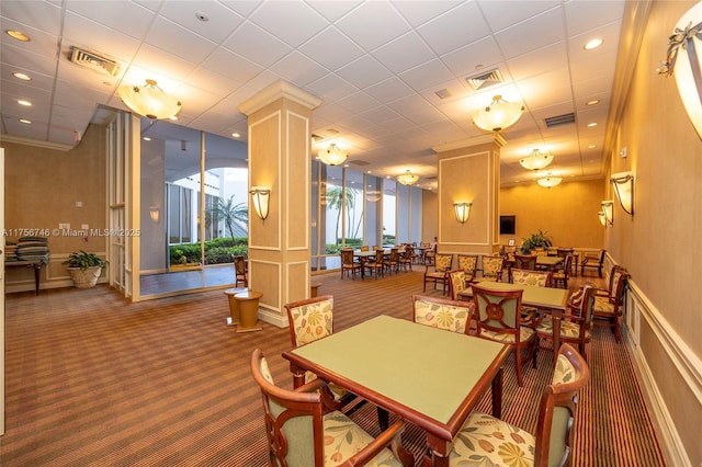 dining room with visible vents, carpet, decorative columns, and a decorative wall