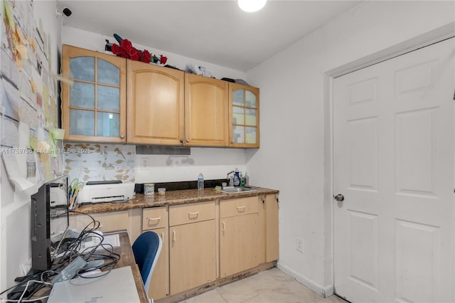 kitchen featuring light brown cabinets, baseboards, a sink, glass insert cabinets, and marble finish floor