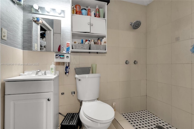 bathroom featuring vanity, tile walls, toilet, and tiled shower