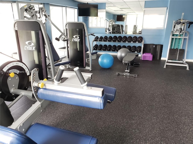 exercise room with a drop ceiling and baseboards