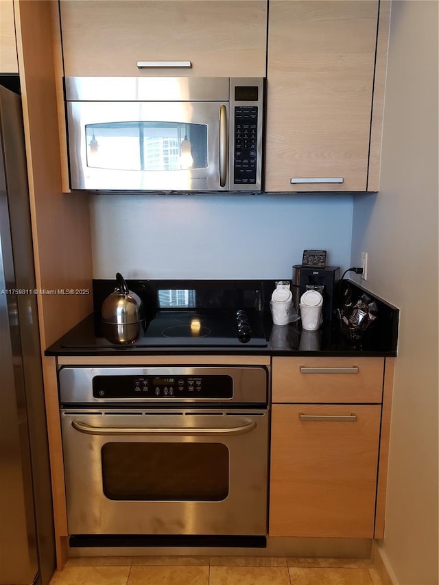 kitchen with dark countertops, light tile patterned floors, and appliances with stainless steel finishes