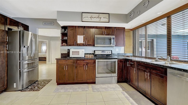 kitchen with dark stone countertops, light tile patterned floors, open shelves, a sink, and appliances with stainless steel finishes