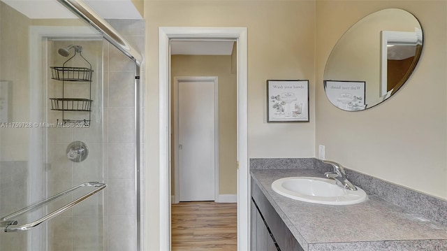 full bath with a stall shower, vanity, and wood finished floors