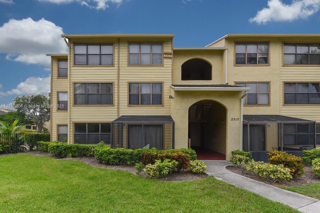 view of property with stucco siding, a front lawn, and fence