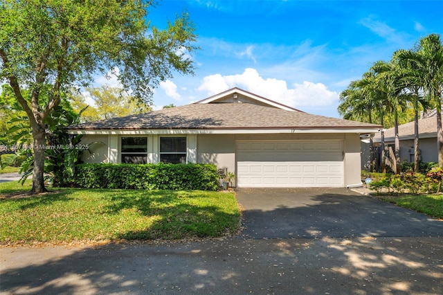 ranch-style home featuring aphalt driveway, a garage, a front yard, and stucco siding