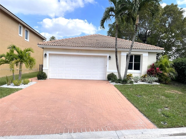 view of front of home featuring an attached garage, a tiled roof, decorative driveway, and stucco siding