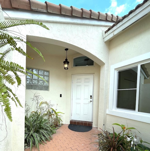 doorway to property featuring a tiled roof and stucco siding