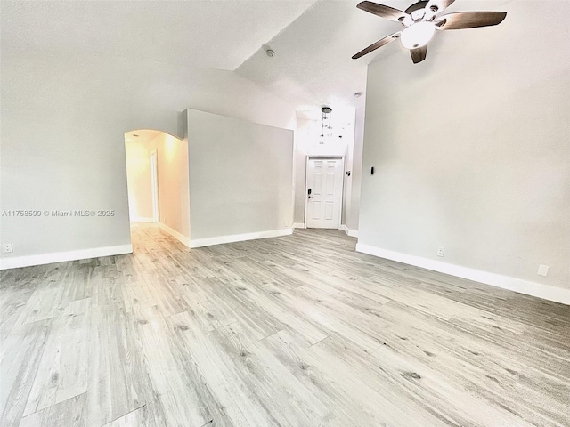 spare room featuring baseboards, arched walkways, vaulted ceiling, and wood finished floors