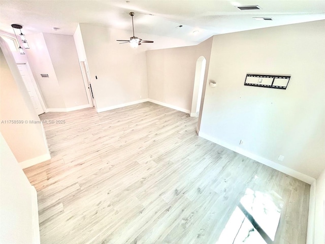 spare room with arched walkways, ceiling fan, visible vents, light wood-style floors, and vaulted ceiling