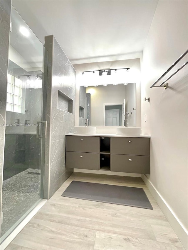 full bath with a stall shower, a sink, and wood finished floors