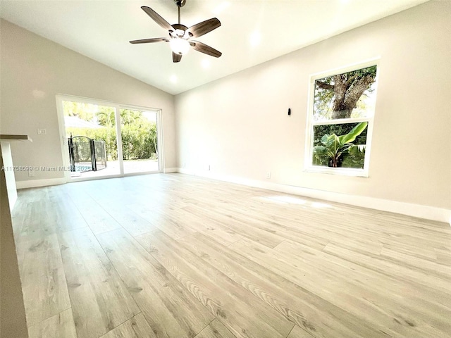 unfurnished living room with lofted ceiling, ceiling fan, light wood finished floors, and baseboards