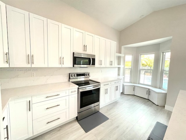 kitchen with vaulted ceiling, open shelves, appliances with stainless steel finishes, and white cabinets