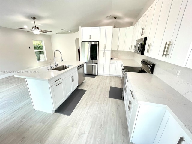 kitchen with an island with sink, stainless steel appliances, light wood-style floors, white cabinetry, and a sink