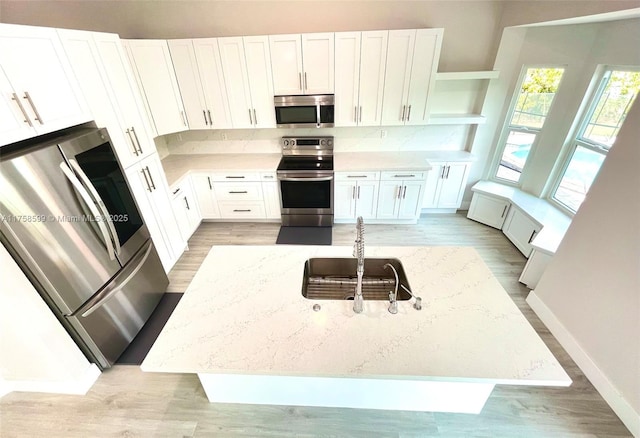 kitchen with white cabinets, light stone countertops, appliances with stainless steel finishes, and open shelves