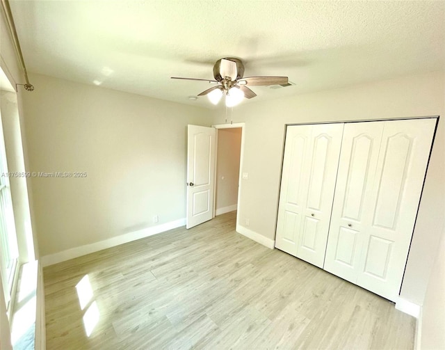 unfurnished bedroom featuring a textured ceiling, light wood finished floors, a closet, and baseboards