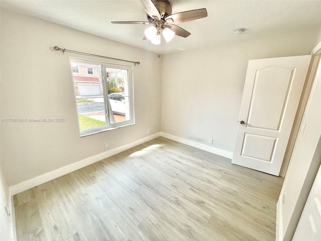 unfurnished room with a textured ceiling, light wood-type flooring, a ceiling fan, and baseboards