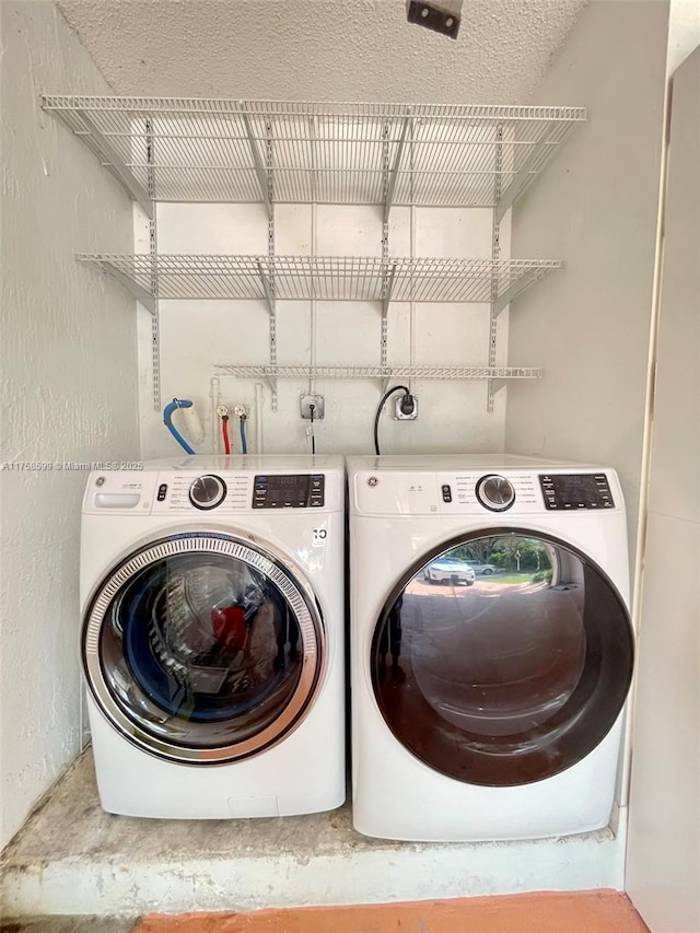 washroom with a textured wall, laundry area, and washer and clothes dryer