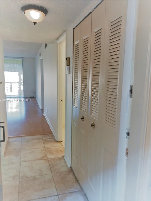 corridor featuring a textured ceiling and baseboards