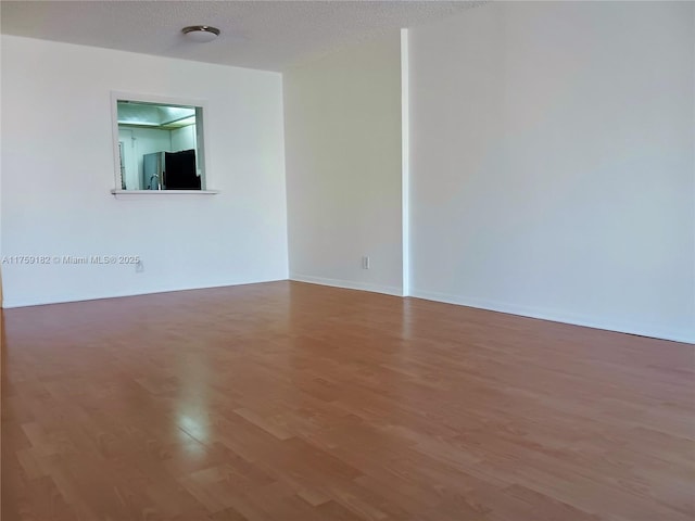 spare room with a textured ceiling and wood finished floors